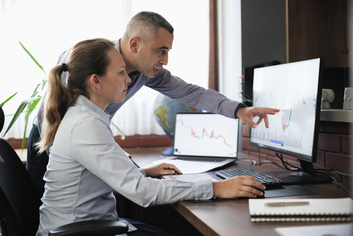 Two people looking at a graph on a computer screen.