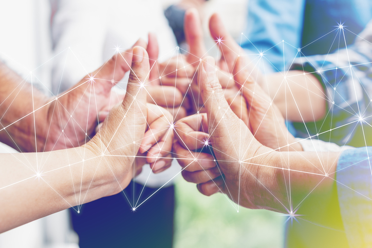 Seven hands meeting together, all with a "thumbs up" gesture.